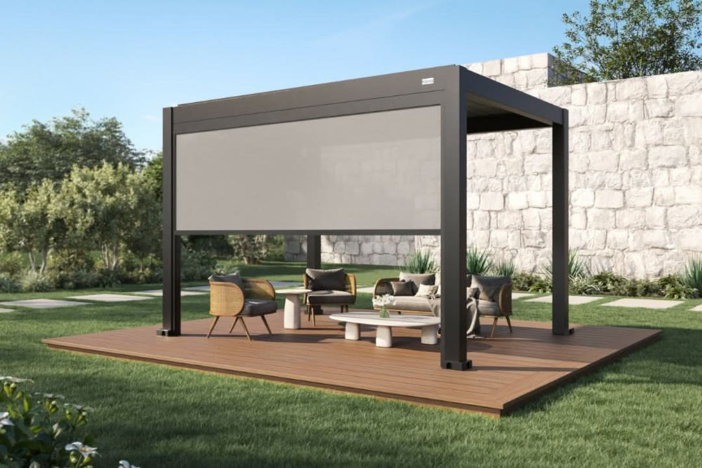 A modern freestanding aluminum pergola with a retractable privacy screen, creating a shaded outdoor lounge area on a wooden deck in a landscaped backyard.